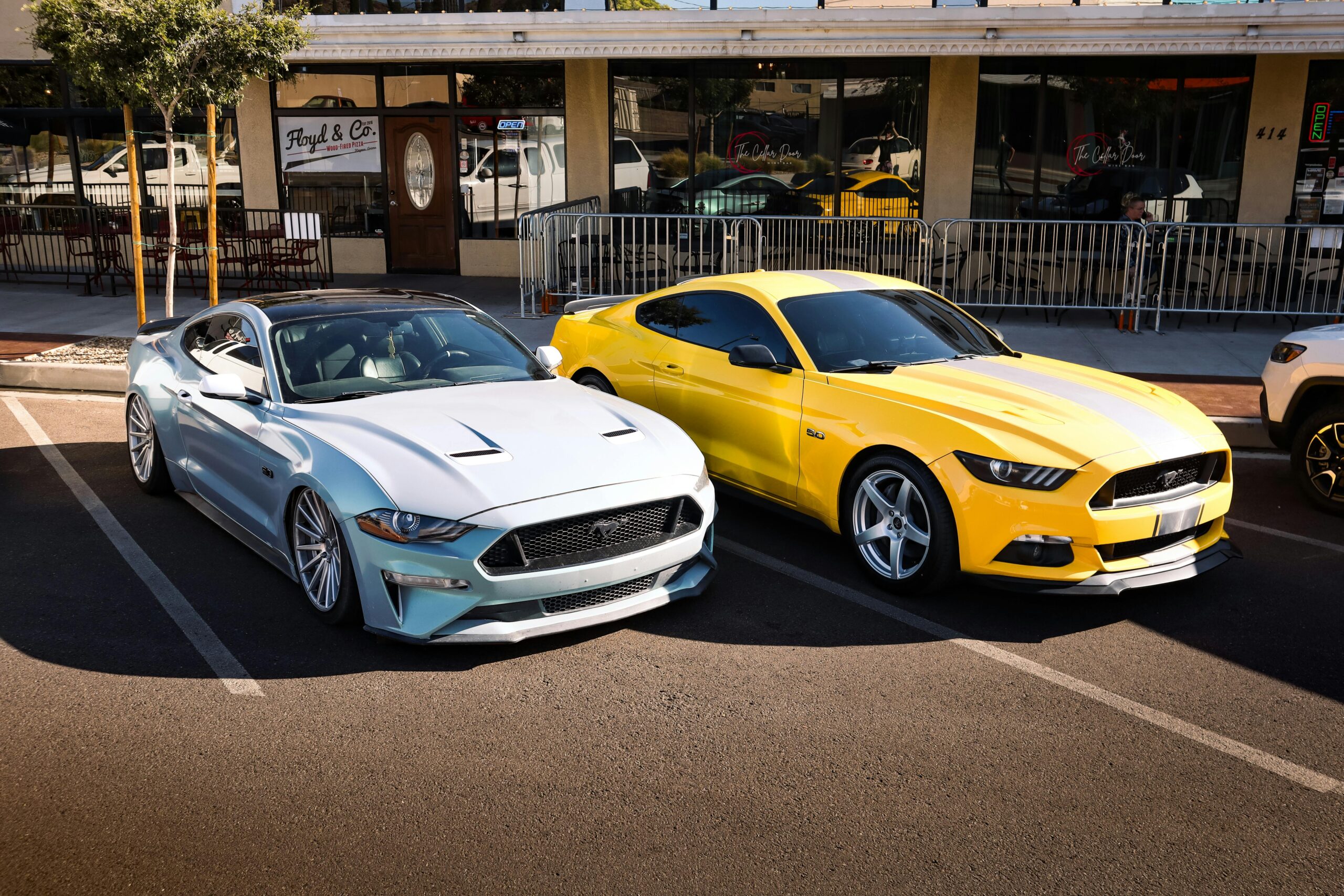 Modern sports cars, one silver and one yellow, parked in an outdoor lot